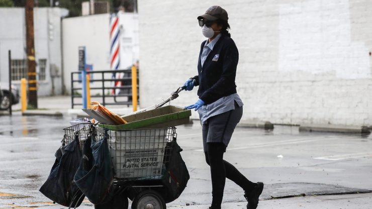 A U.S. Postal Service worker wears a mask and gloves while delivering mail on April 9 in Van Nuys, California.