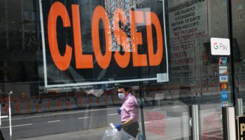 A closed sign is displayed in the window of a business in a nearly deserted lower Manhattan.