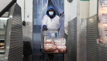 An employee at work in the meat department of a Florida supermarket. Such workers are considered essential and are taking risks during the pandemic but are not highly paid.
