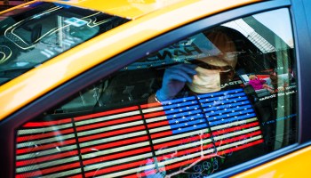 A taxi driver wears a face mask and gloves as he drives down Times Square on March 26 in New York City.