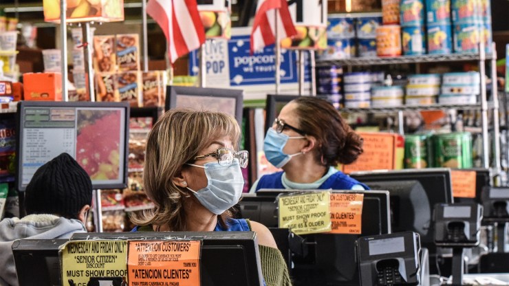 Cashiers wearing protective masks work in a grocery store in Brooklyn on April 2.