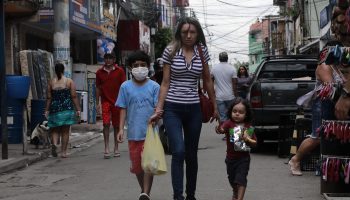 A family walks down the street in Sao Paulo, Brazil. The value of that nation's currency, the real, has plummeted.