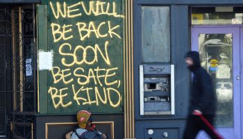 Writing on a business window reads "We will be back soon. Be safe, be kind."