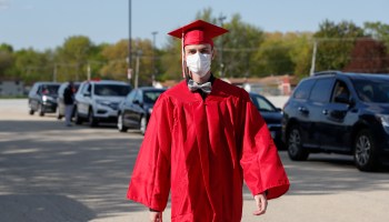 A graduate student arrives to pick up his diploma wearing a mask