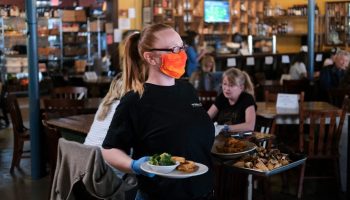 A waitress wearing gloves and a mask carries food at a Tennessee restaurant on April 27.