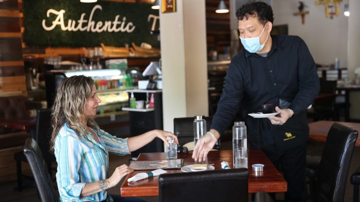 A masked waiter serves a customer at a reopened restaurant in Florida on May 11.