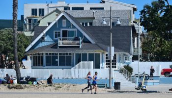 Joggers pass a beachfront bungalow in Southern California. People who now work remotely might seek a temporary stay in a pleasant spot.
