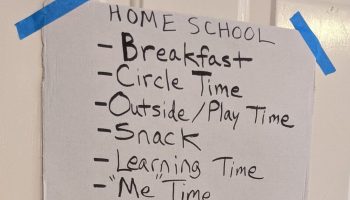 A schedule for kids at home during COVID-19 is taped up on the cupboard