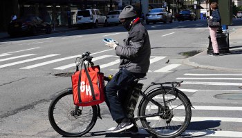 A Grubhub delivery worker waits at a New York City intersection.