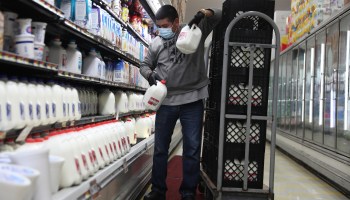 An employee restocks milk at a grocery store. Some businesses are seeing strong demand during the pandemic and increasing staff hours.