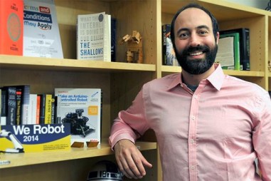A photo of Ryan Calo, a law professor at the University of Washington, standing next to a bookshelf.