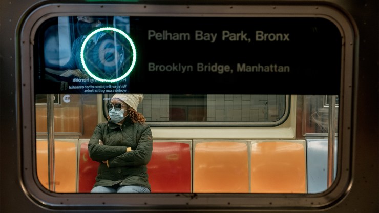 A commuter wearing a face mask rides the subway.