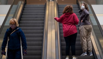 People ride an escalator at a reopened mall.
