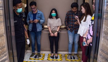 People stand in designated areas of an elevator to ensure social distancing.