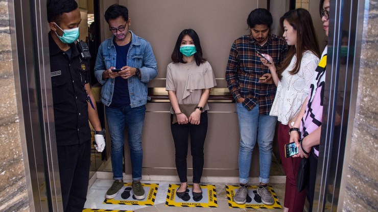 People stand in designated areas of an elevator to ensure social distancing.