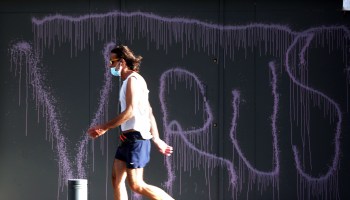 A man passes graffiti about the coronavirus in Beirut, Lebanon.