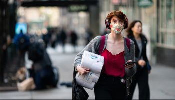 A woman wearing a mask in New York City. Financial experts believe that the virus-suppression effect of wearing face masks helps to preserve economic activity.
