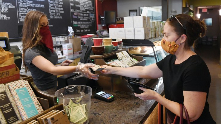 A woman makes a purchase at a Nevada coffee shop. Some small business owners are applying for PPP loans now because they weren't sure whether they were eligible before.