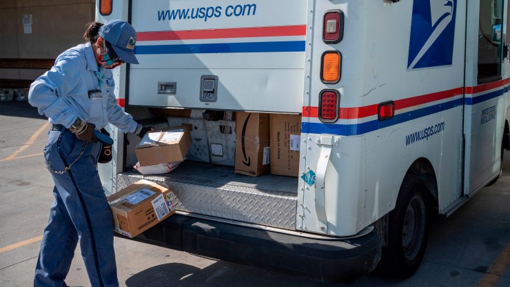 A USPS mail carrier loads her truck in El Paso, Texas, in April.