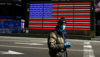 A man walks past a digital American flag in Times Square in New York City in March.