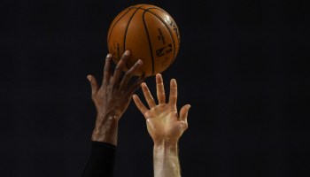 Players' hands reach for a basketball.