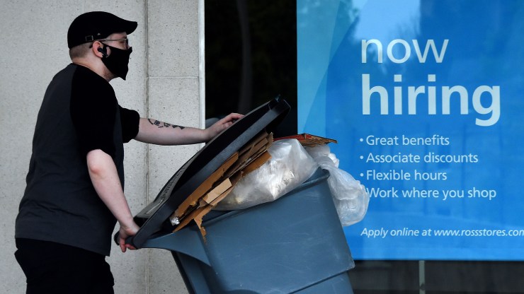 A man wearing a face mask walks past a "now hiring" sign at a business in Arlington, Virginia. Hiring is sluggish across the economy and economists worry that the trend will turn negative.