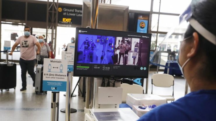 Travelers walk past a system of thermal imaging cameras looking for fevers, part of a test at Los Angeles International Airport in June.