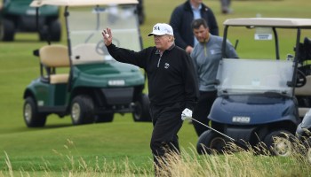 President Donald Trump waves while playing golf at the Trump Turnberry resort in Scotland.