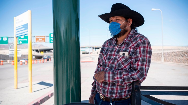 A man in Texas waits for a bus to take him across the border to Mexico. Travel and commerce are down in the area.