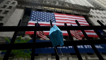A face mask hangs on a fence outside the New York Stock Exchange. Corporate borrowing has slowed as companies reconsider the economic future.