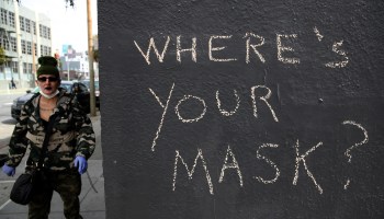 A person walks by graffiti encouraging mask wearing in April in San Francisco.