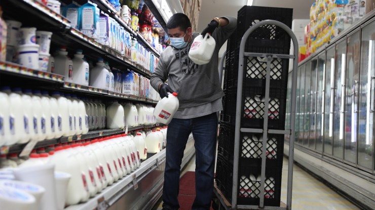 An employee restocks the milk shelves at a Miami supermarket in April.