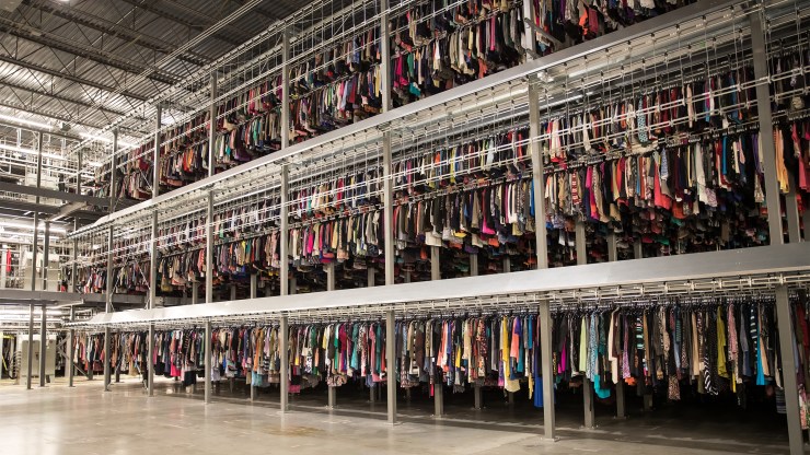Used items fill three-level racks in a thredUP distribution center.