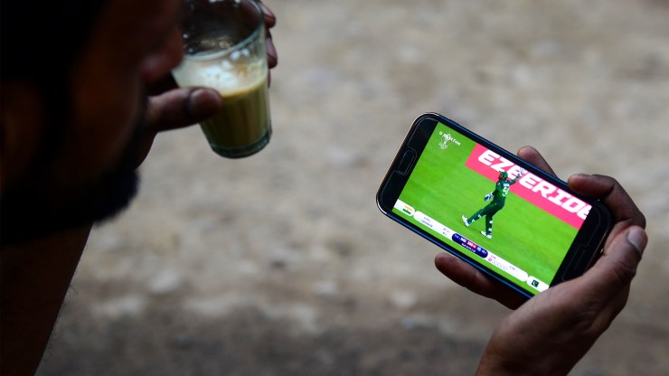 A man watches a live soccer match on his smartphone.