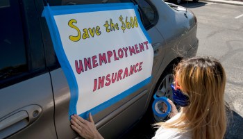 An activist in Las Vegas tapes a sign to her car in support of extending the $600 weekly unemployment benefit, which expired at the end of July.