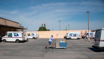 A mail carrier pushes a cart out of a United States Postal Service sorting facility at the Remcon Circle United States Postal Service Post Office amid the coronavirus pandemic in on April 30, 2020 in El Paso, Texas.