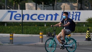 A man rides past the offices of Tencent, the parent company of Chinese social media platform WeChat, in Beijing.