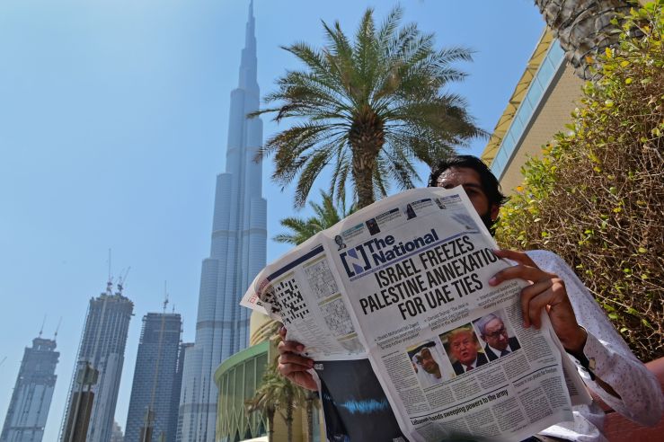 A man in Abu Dhabi reads a newspaper featuring a front-page story about diplomatic agreement between Israel and the United Arab Emirates.