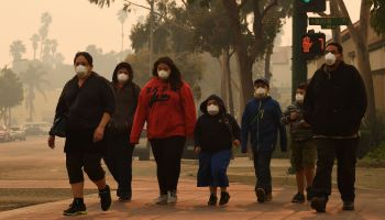 A family wears face masks as they walk through the smoke-filled streets after the Thomas wildfire swept through Ventura, California, on Dec. 6, 2017.