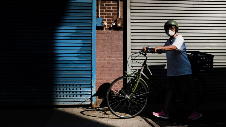A person walks with a bike in New York City. The coronavirus pandemic battered bicycle manufacturing but boosted demand.