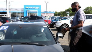 A car salesman talks to customers at a New York dealership in June. Durable goods orders rose in July, led by a surge in demand for cars.