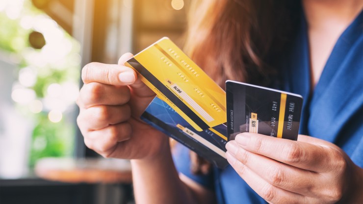 A woman holding three credit cards. The changes in household debt in the second quarter were driven by a decline in credit card balances as consumer spending dropped.