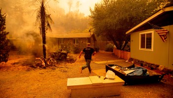 A resident runs into a home to save a dog while flames from the Hennessey fire get closer in Napa, California, on Aug. 18.