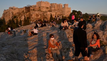 People enjoy a sunset on the Areopagus hill overlooking the ancient Acropolis in Athens in May.