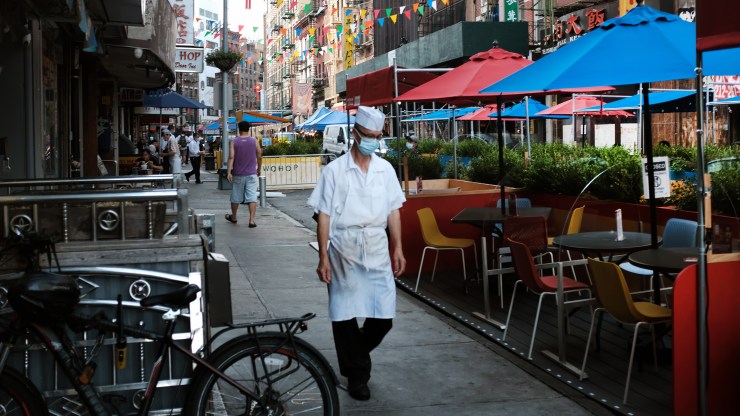 A worker walks past an outdoor dining area in New York on Aug. 10.