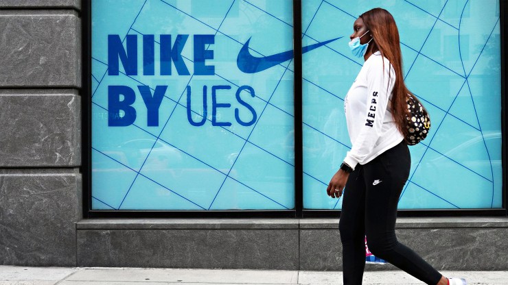 A woman wearing Nike attire walks past a Nike store in New York on Aug. 25.