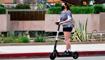 A commuter on an electric scooter wears a face mask in Los Angeles in June.
