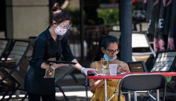 A waiter wearing a face mask serves a customer outdoors at a Maryland restaurant in June.