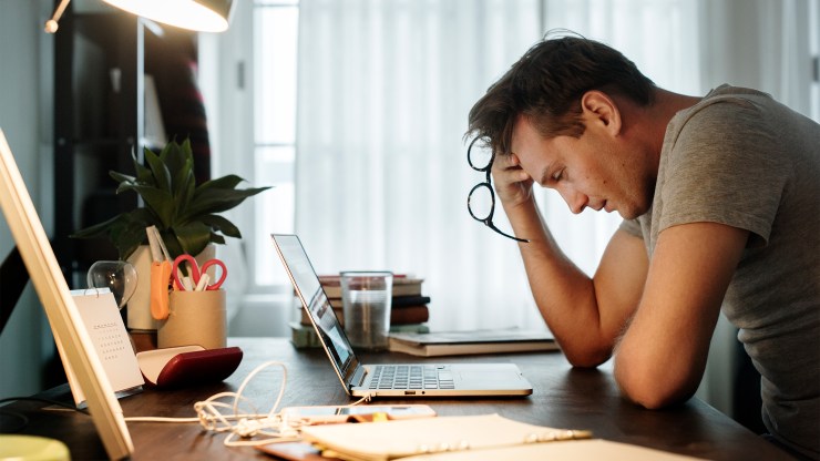 A man is stressed out while working on his laptop at home.