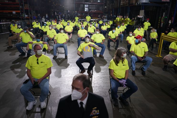 Workers at an Owens & Minor Inc. medical supplies distribution center in Allentown, Pennsylvania, wait for President Donald Trump, on May 14. One of them is lifting his shirt to reveal a Q shirt underneath.